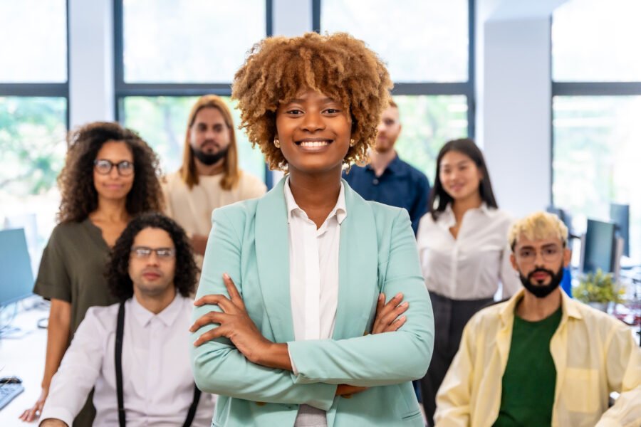 Proud black entrepreneur standing with arms crossed in a coworking. Proud african entrepreneur standing with arms crossed next to coworkers in the office