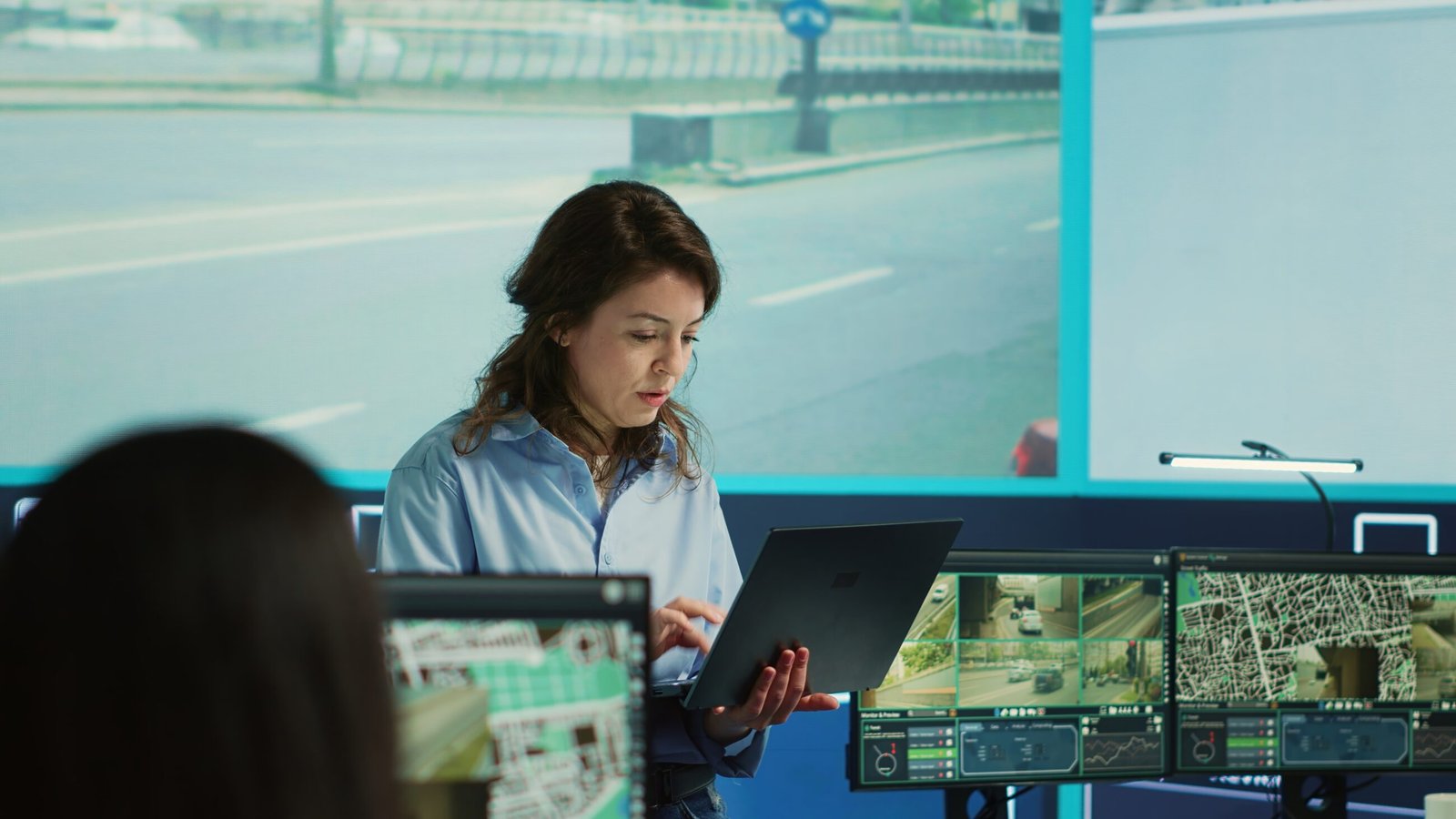 Supervisor gathering intelligence from satellite based surveillance footage, diverse team of operators analyzing traffic through security cameras. Control center license plate reading. Camera A. Crew Wellbeing.