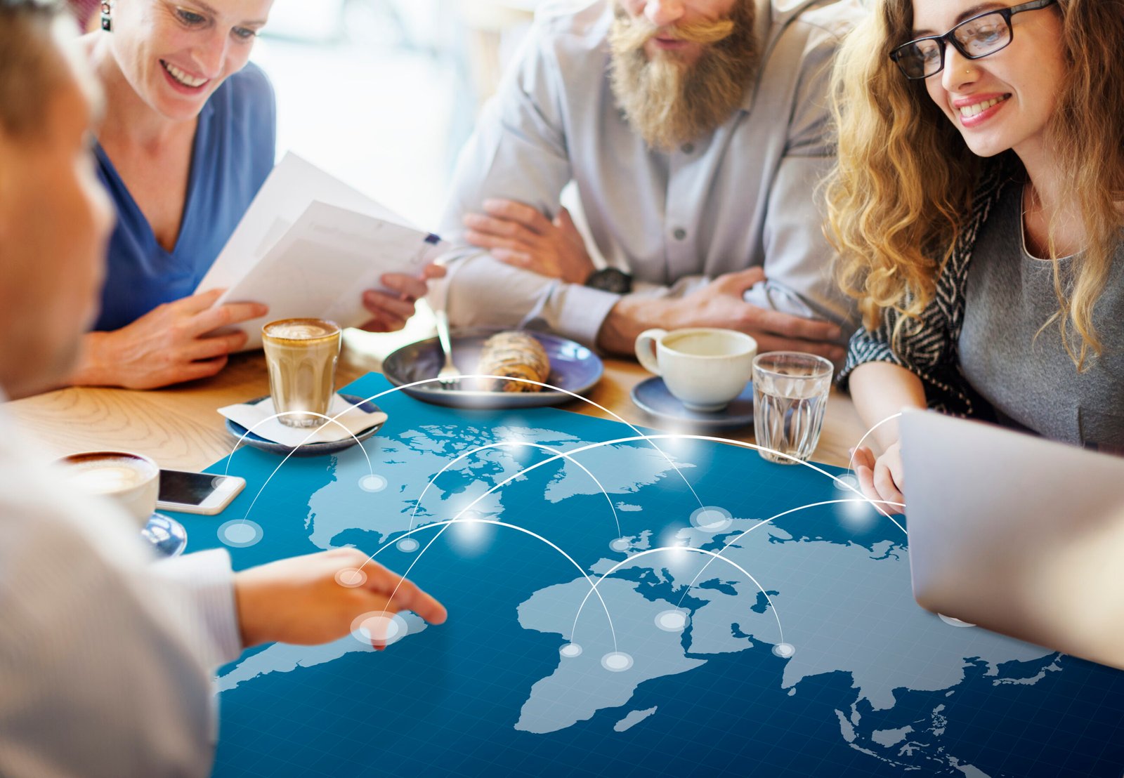 Business professionals discussing international strategy with a world map. Cross-border workforces create complex compliance challenges.