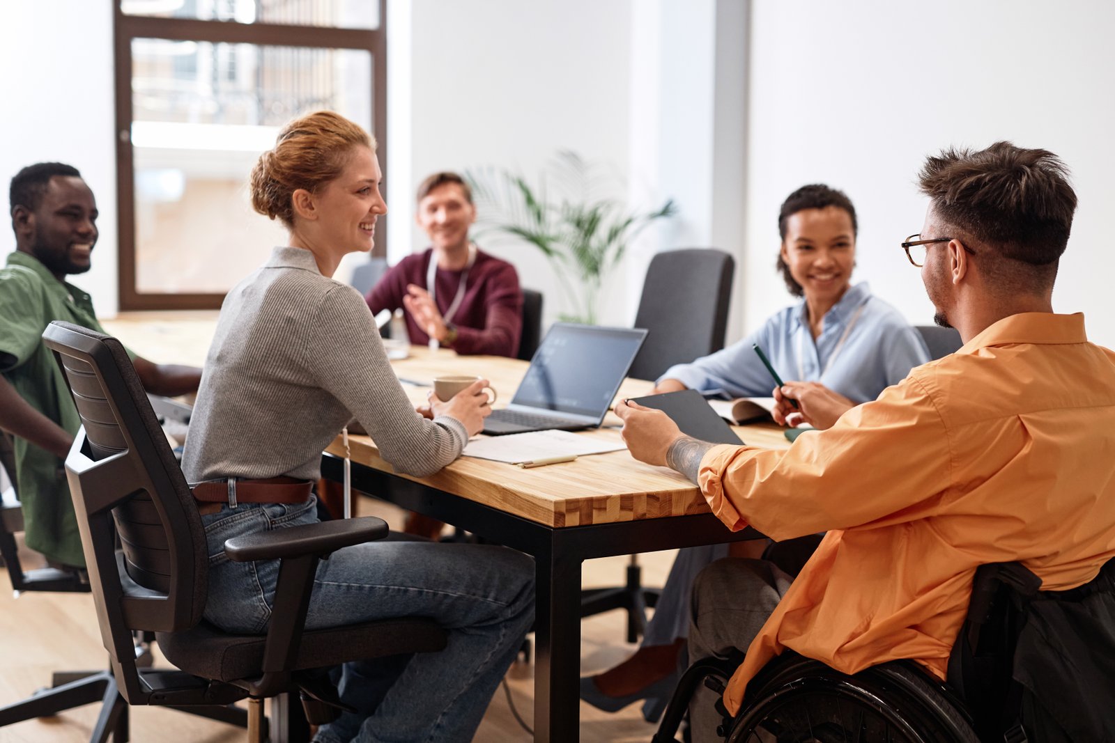 Diverse team collaborating around a table during a workplace meeting. Scalable HR frameworks for companies in Malta.