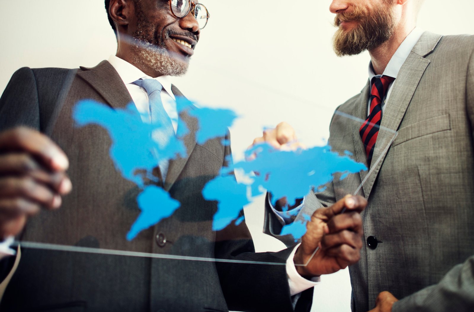 Colleagues collaborating around a world map, representing global business connections and international teamwork. Cross-border workforces create complex compliance challenges.