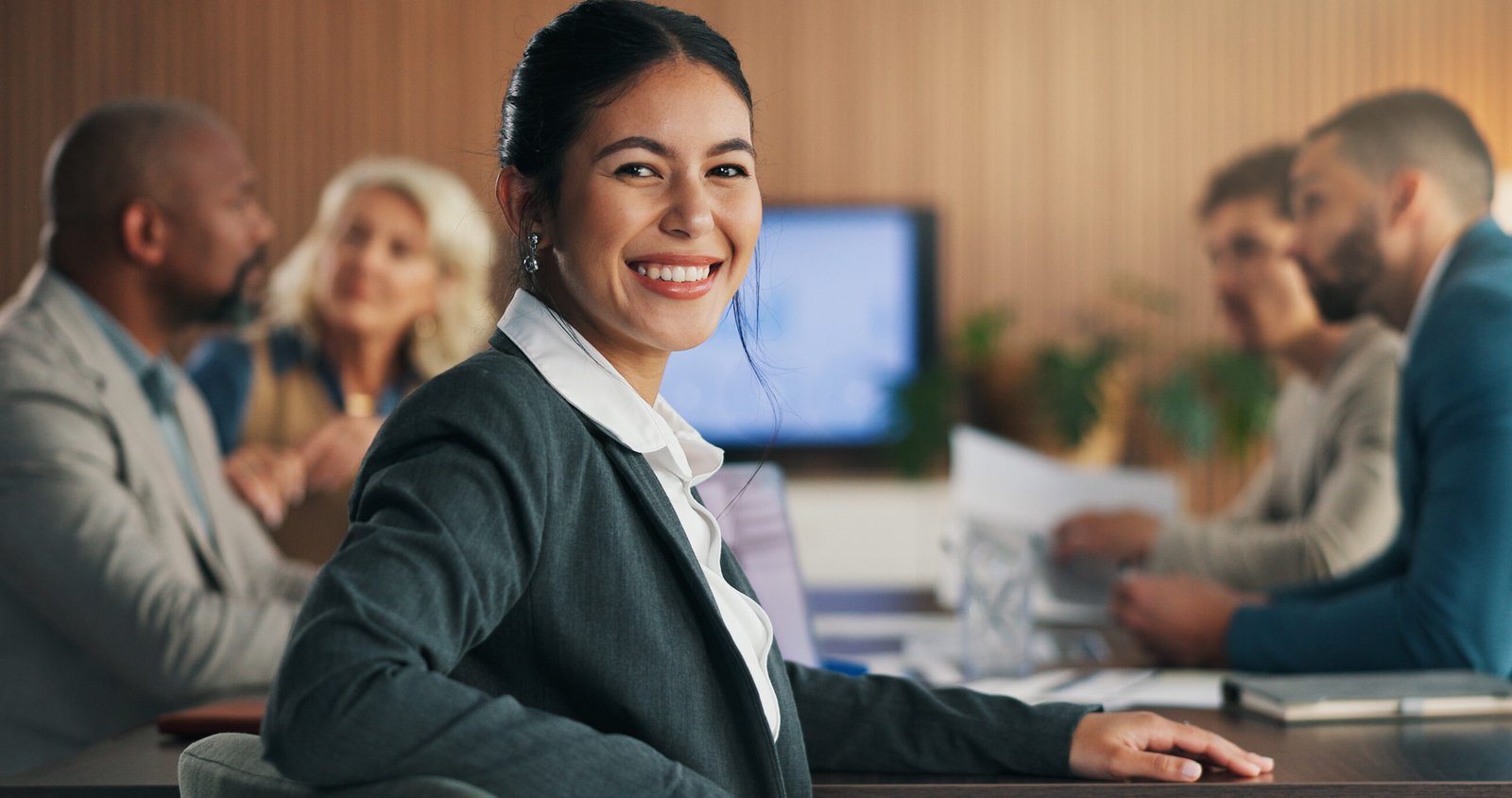 Professional woman smiling during a business meeting with colleagues in the background. Legal terminations in Malta.