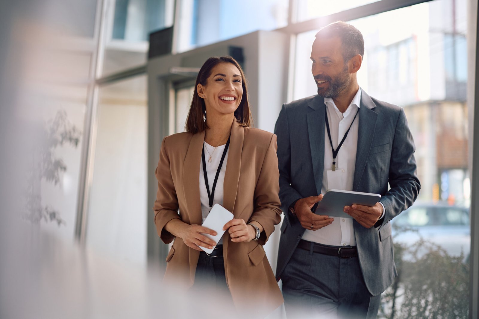 Two business professionals smiling while walking through an office.