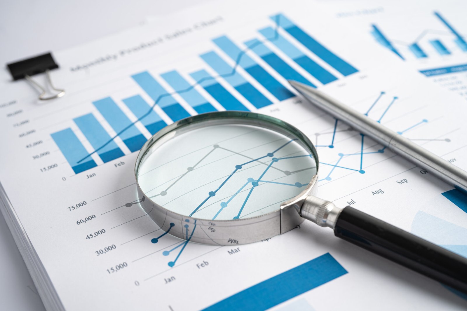 Magnifying glass over financial charts and data on a report.